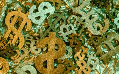 Colorful paper currency symbols scattered on a crinkled surface.