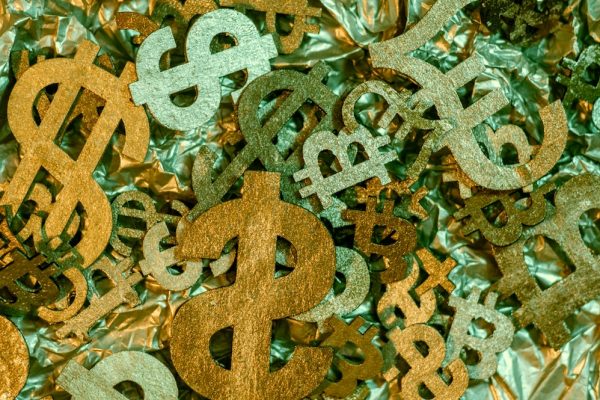 Colorful paper currency symbols scattered on a crinkled surface.